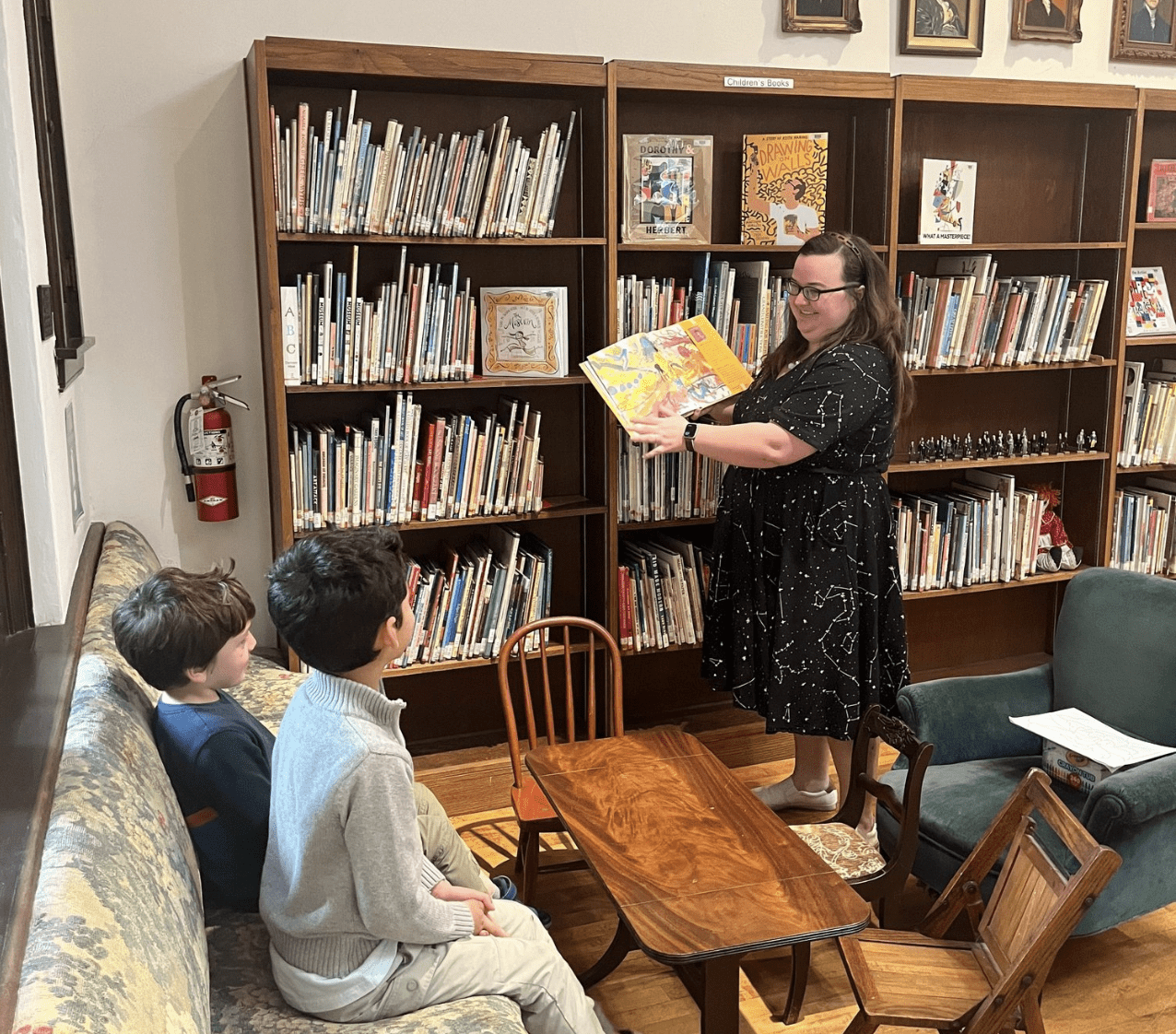 lady reading to two little boys in a library setting